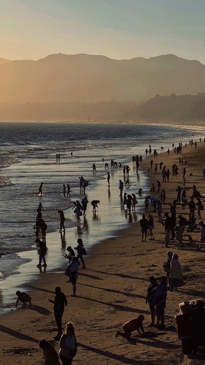 Crowd enjoying a sunset at Santa Monica Beach, with silhouettes against the horizon.