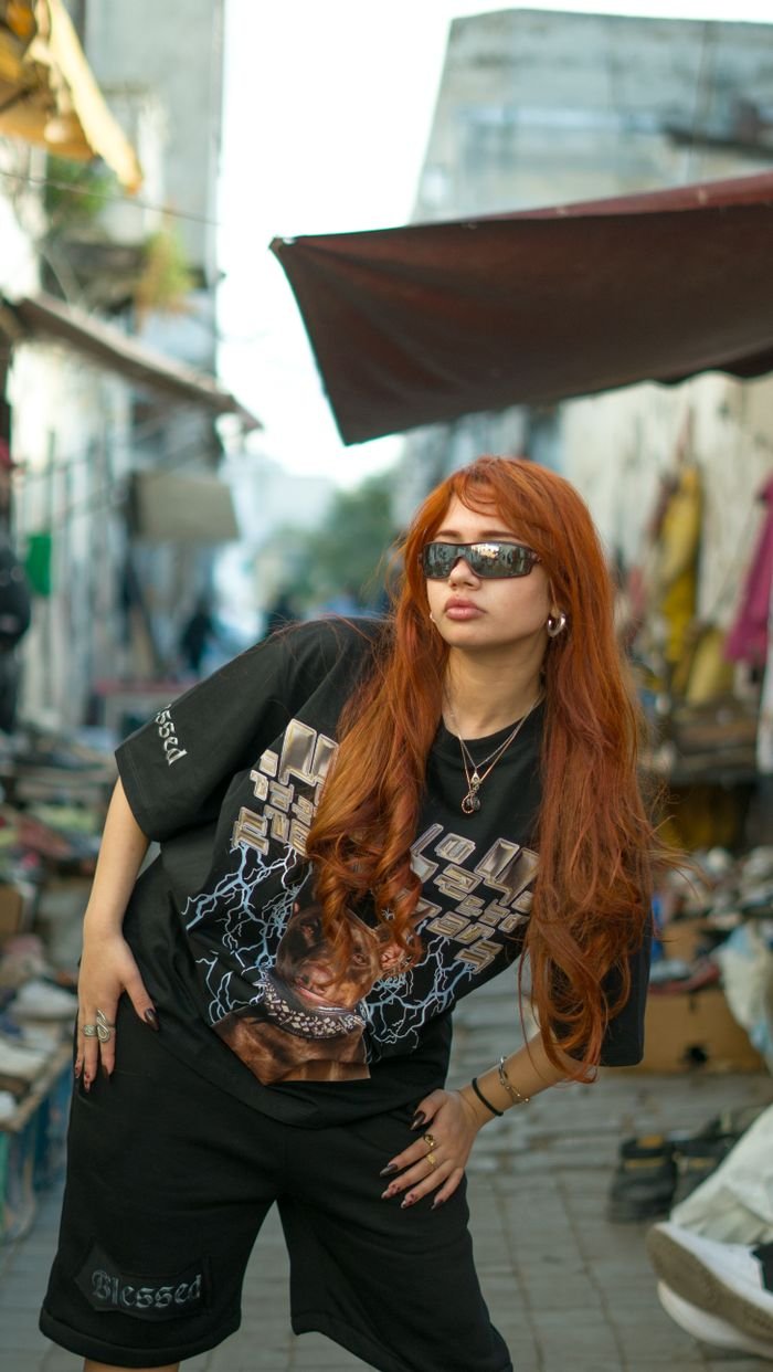 Fashionable woman with red hair posing confidently in a vibrant Moroccan street market.